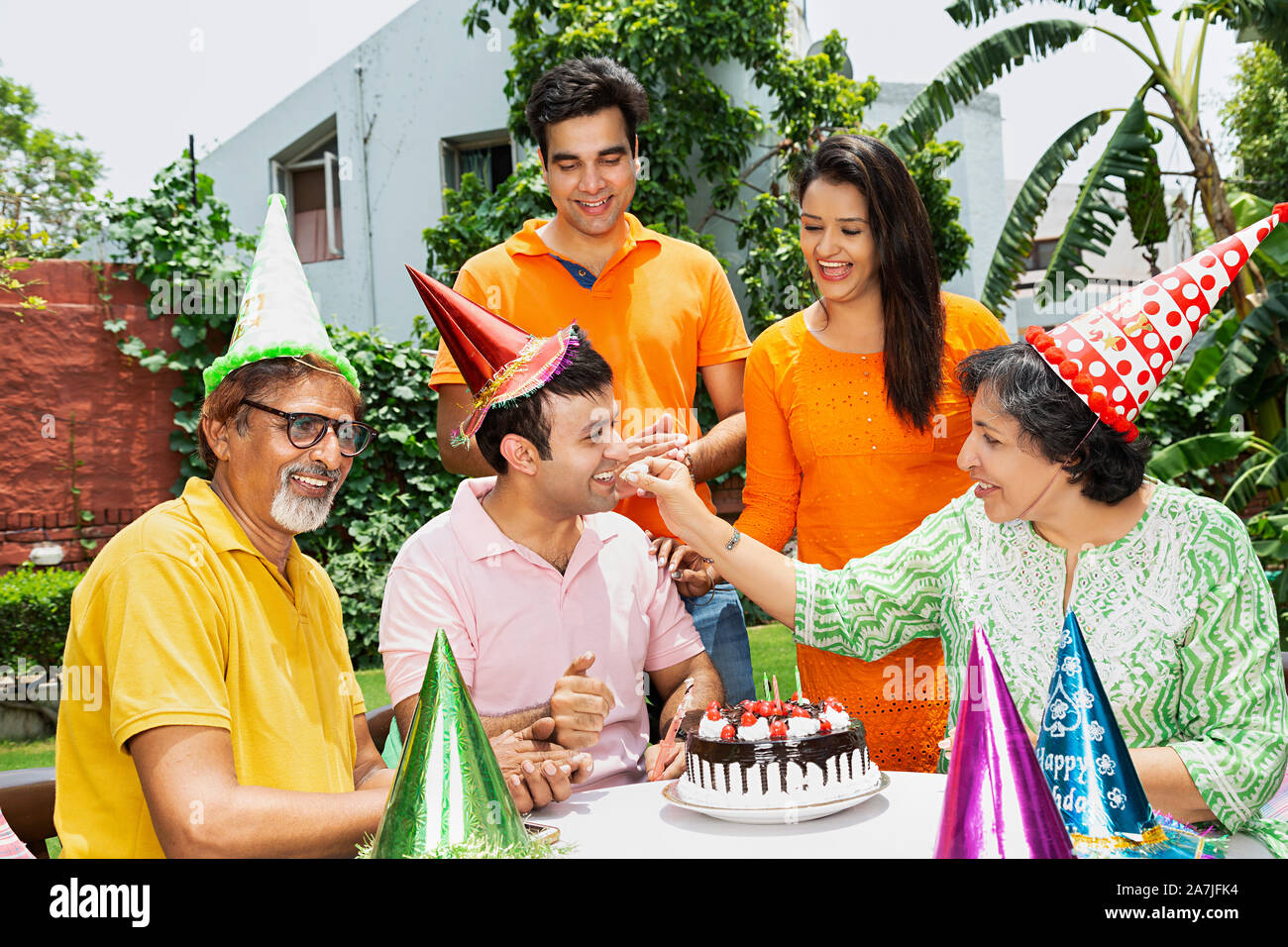 Glückliche Familie feiert Geburtstag Mutter füttern Ihr erwachsener Sohn Kuchen im Innenhof in der Nähe Ihres Hauses Stockfoto