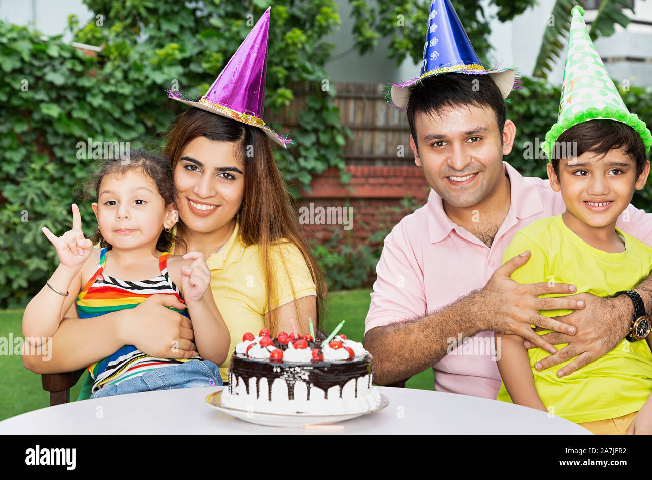 Glückliche junge Familie Eltern und zwei Kinder feiern Geburtstag zusammen in - Hof - Ihr Haus Stockfoto