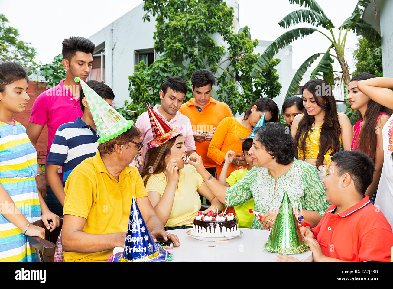 Group-Of gerne große Familien feiern Geburtstag Mutter füttern ihre Tochter Kuchen - am Hof - Ihr Zuhause Stockfoto