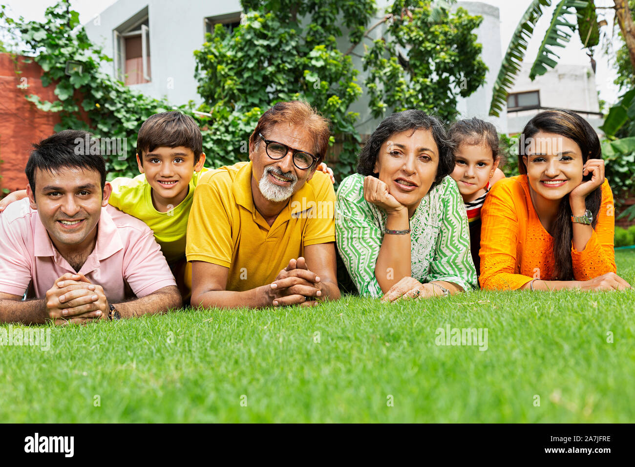 Gerne drei Generation Familie Lügen-auf-Gras entspannende Zusammen vor ihrem Haus im Garten Stockfoto