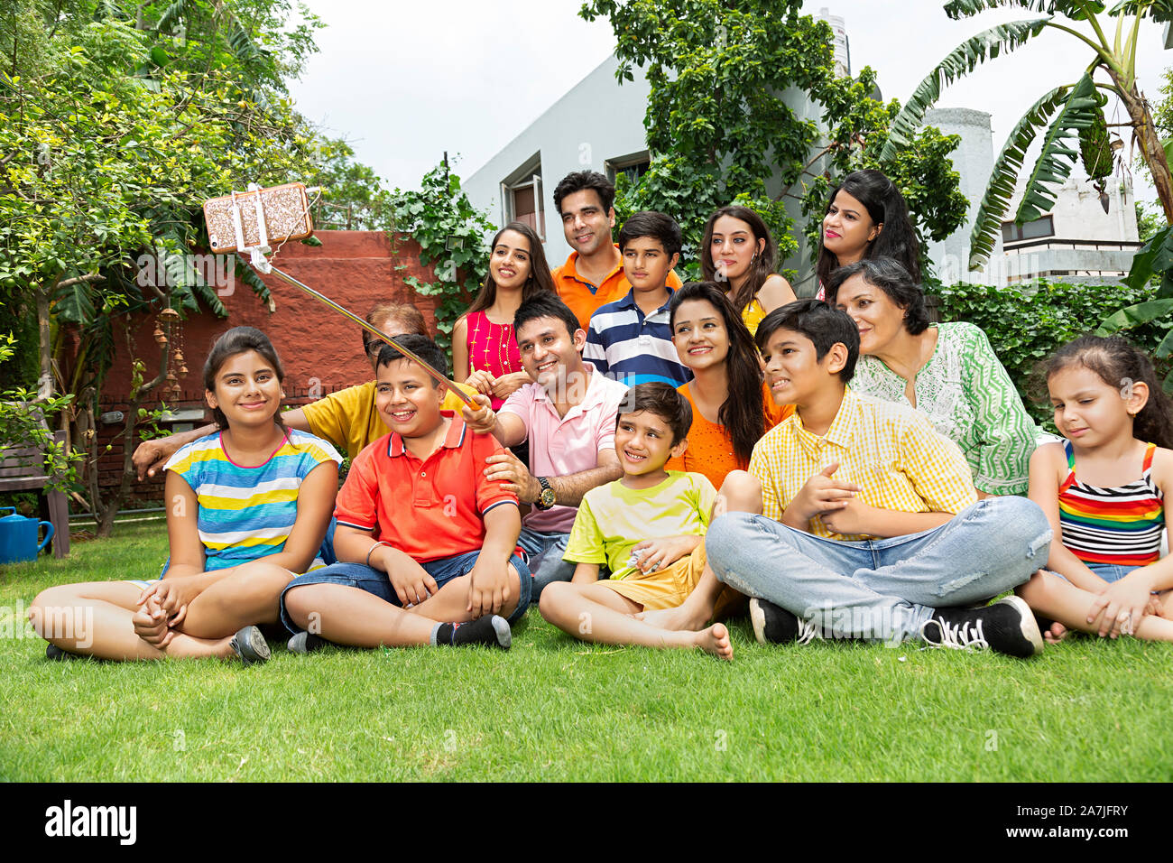 Große Gruppe - von Indischen - Familie Mitgliederversammlung unter Selfie Foto mit Smartphone auf selfie Stick im Innenhof in der Nähe Ihres Hauses Stockfoto
