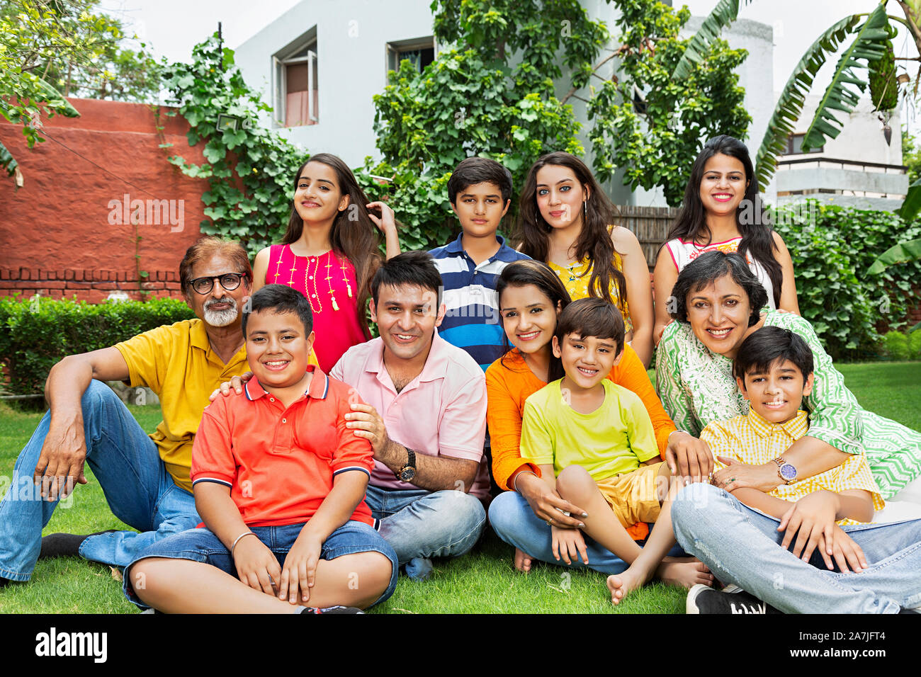 Große Gruppe - von indischen Familie Mitglieder sitzen im Gras zusammen entspannende vor - ihr Haus in den Garten Stockfoto
