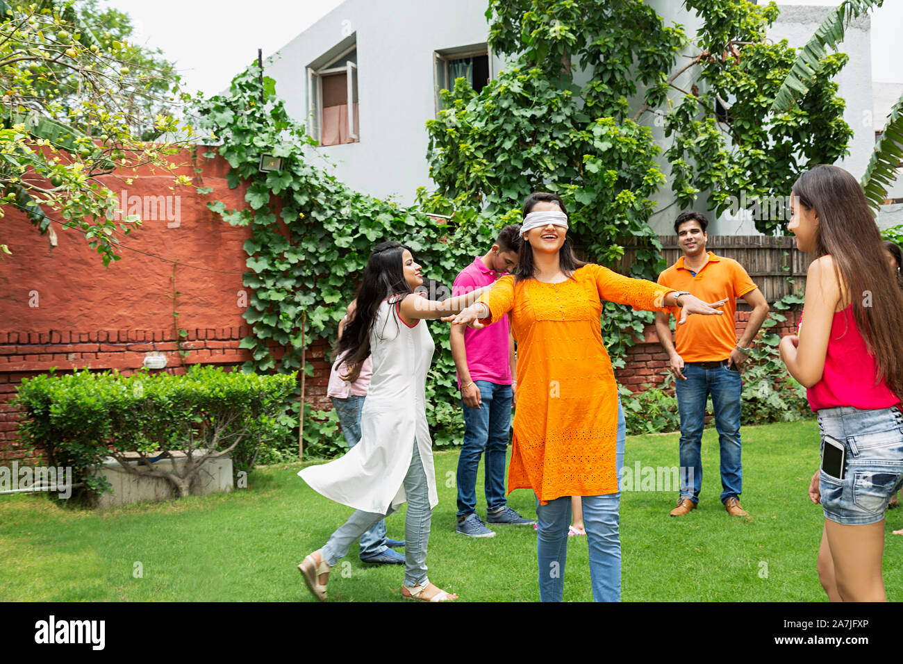 Gruppe - glückliche Familien spielen Versteckspiel Spiel vor ihrem Haus im Garten Stockfoto