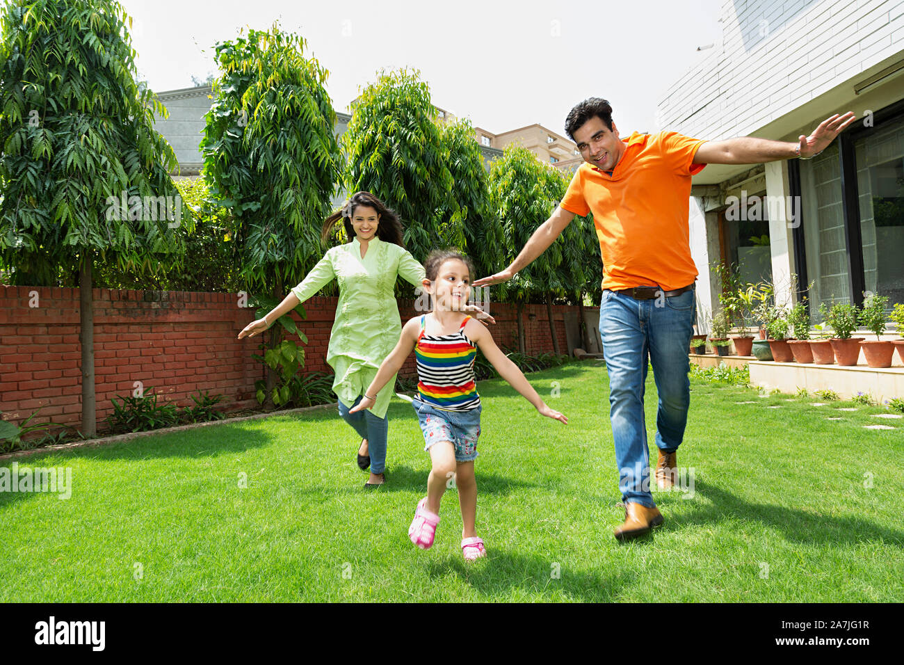 Happy indischer Junge Familie Eltern und kleine Tochter zusammen vor ihrem Haus im Garten Stockfoto