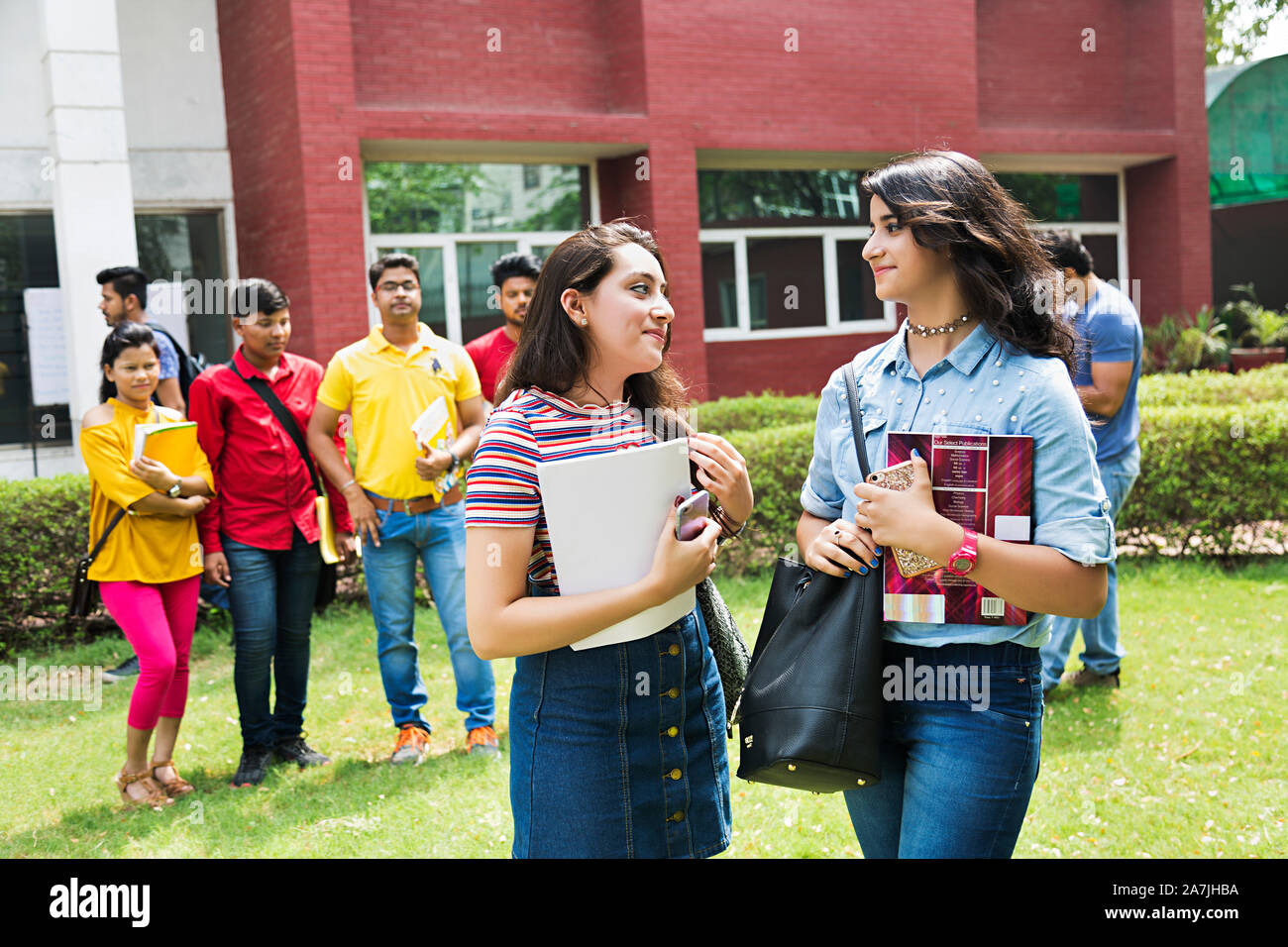 Zwei junge weibliche Studenten Freunde reden Kommunikation mit Klassenkameraden - Hintergrund At-Campus Stockfoto