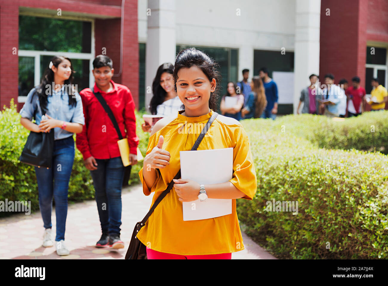 Portrait von Jugendmädchen Student Zeige Thumbs-up mit Mitschülern - Hintergrund At-Campus Stockfoto