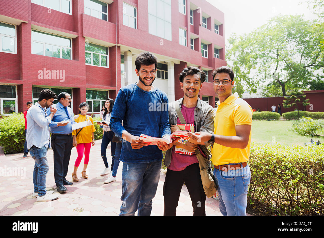Drei College jungen Studenten Freunde lesen Buch zusammen mit People-In - Hintergrund In-Outside Campus Gebäude Stockfoto