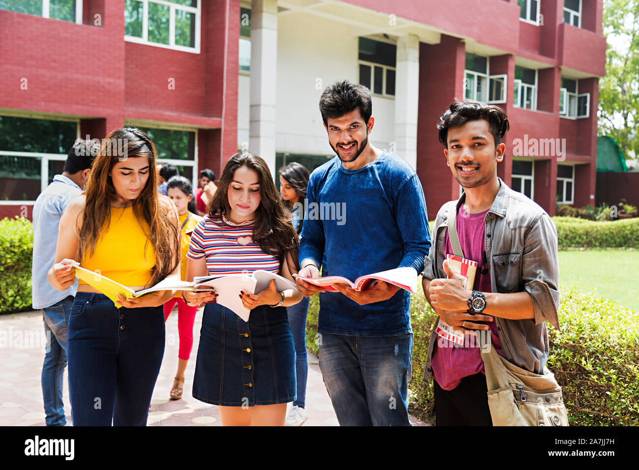 Vier Studenten Freunde Studium Buch zusammen mit People-In - Hintergrund In-Outside Campus Gebäude Stockfoto