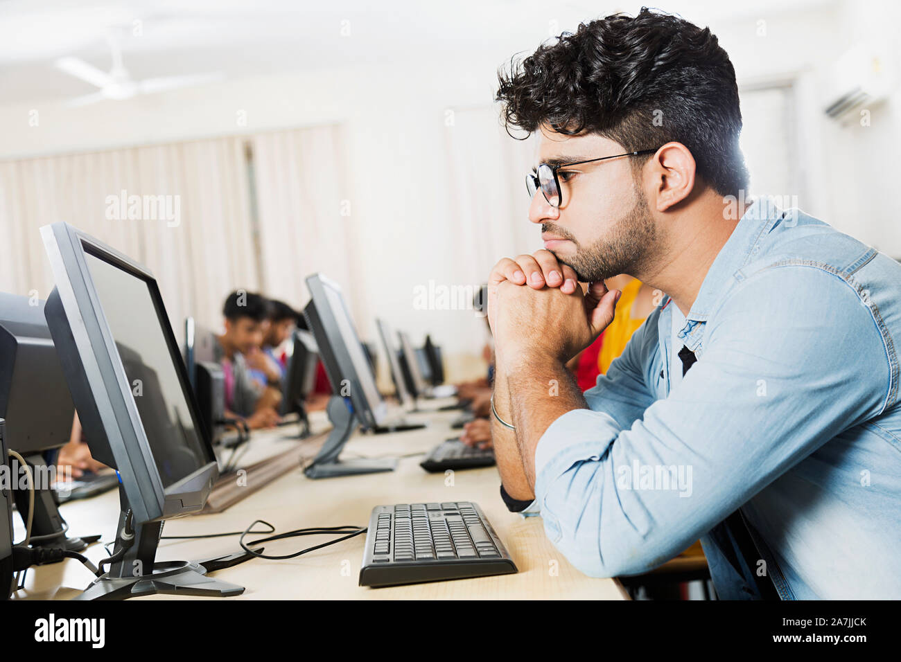 Konzentrieren jungen männlichen Studenten Looking-At Bildschirm Studium E-Learning Bildung in Computer Lab Stockfoto
