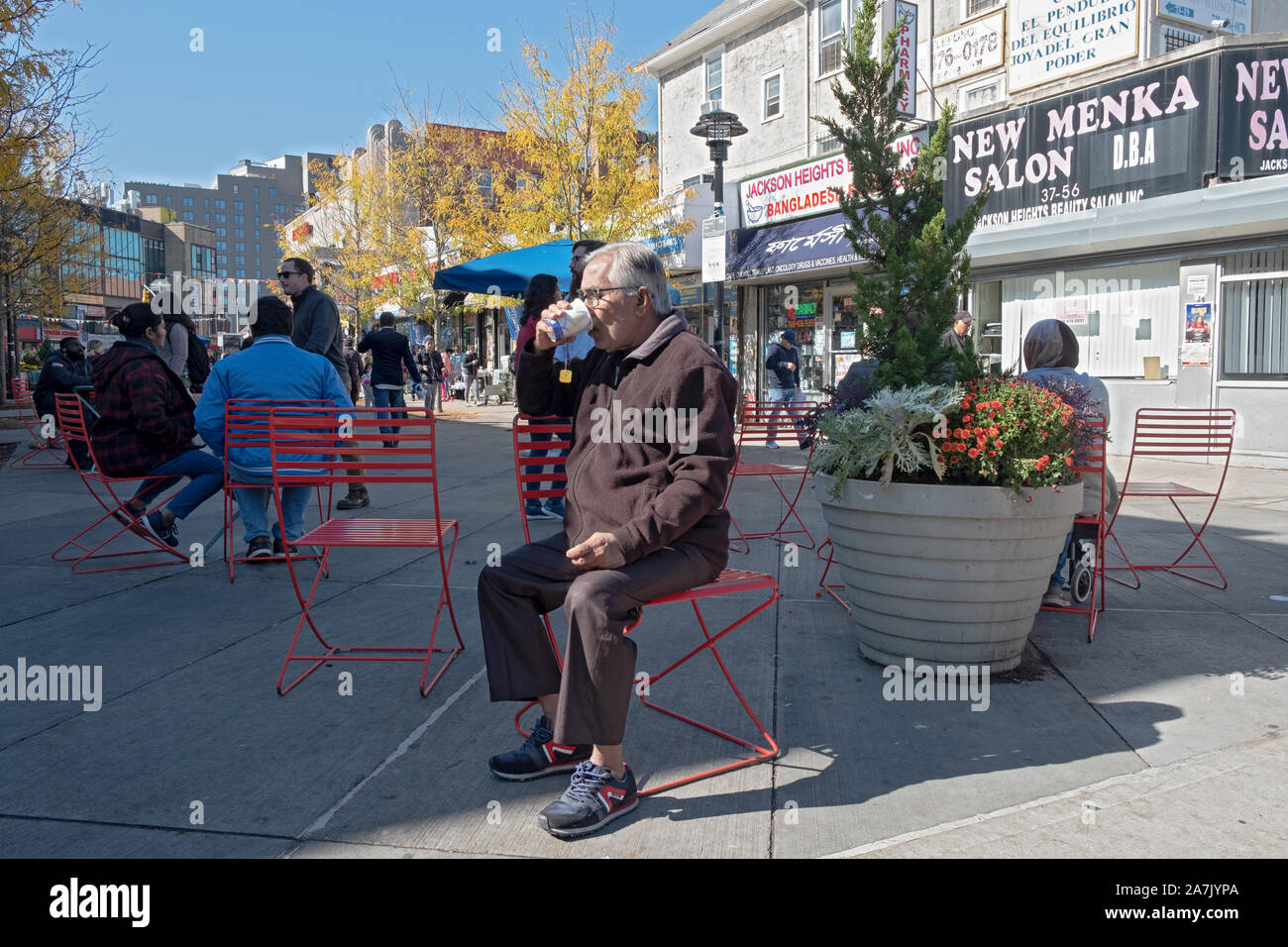 Ein Mann (vermutlich ein Immigrant) Tee trinken in Vielfalt Plaza in Jackson Heights an einem kühlen Herbst Tag. In Queens, New York City. Stockfoto