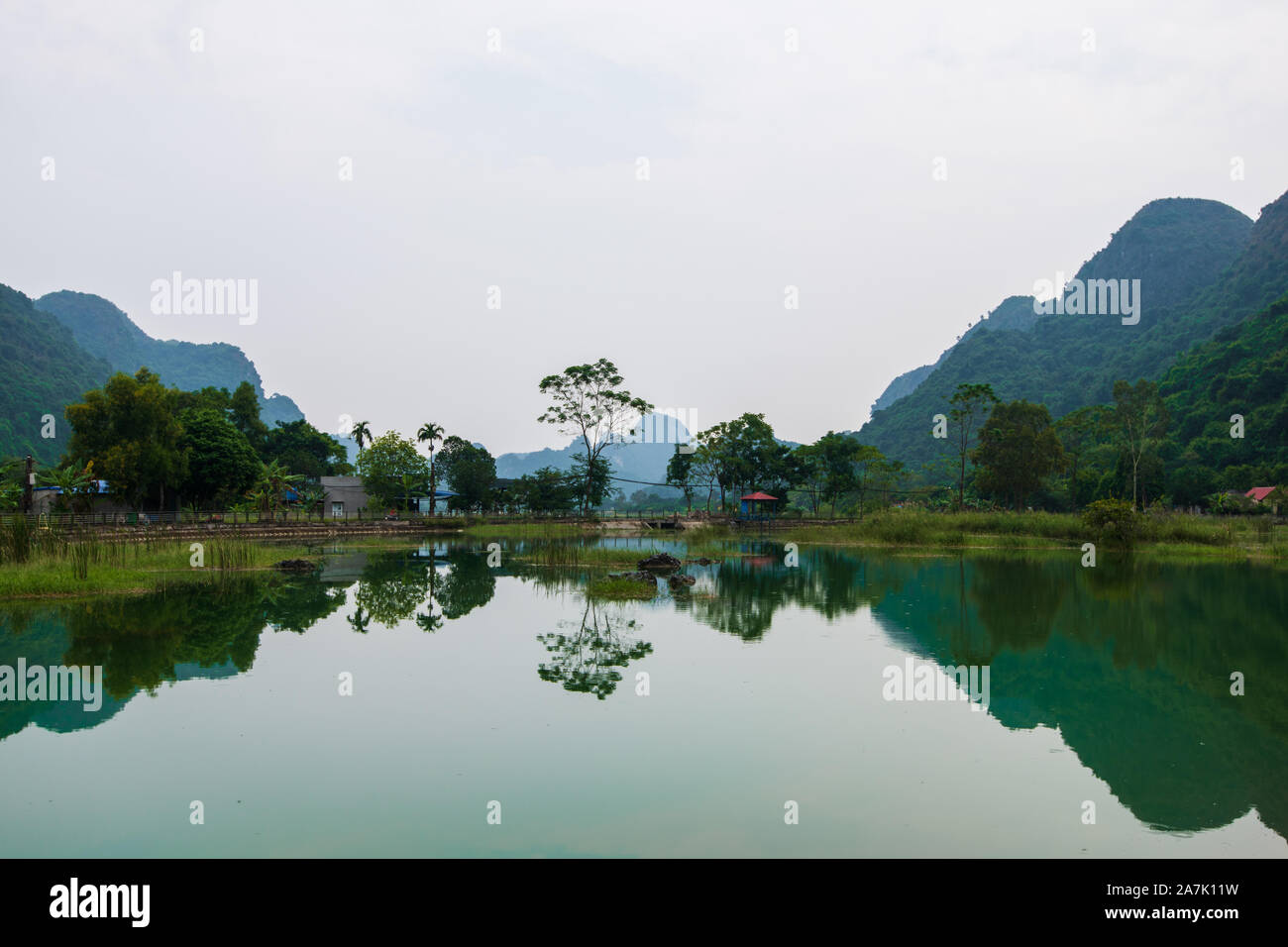 Berge spiegeln sich in eine Glut grüner See auf der versteckten Insel Cat Ba, die regelmäßig mit dem Boot Touren rund um Ha Long Bay besucht wird Stockfoto