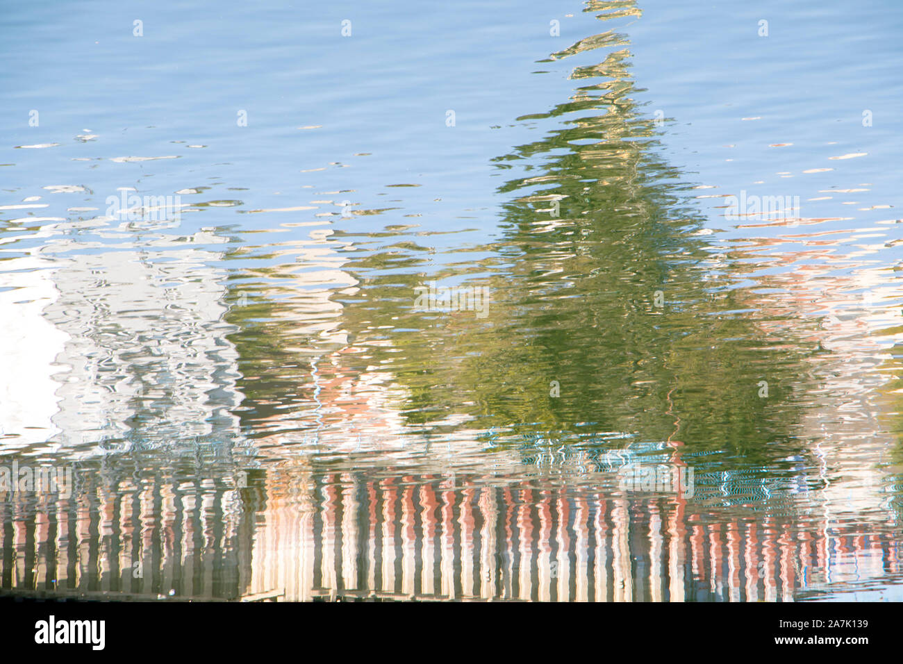 Verschwommene Spiegelungen der Bäume auf dem Fluss an einem sonnigen Tag Stockfoto