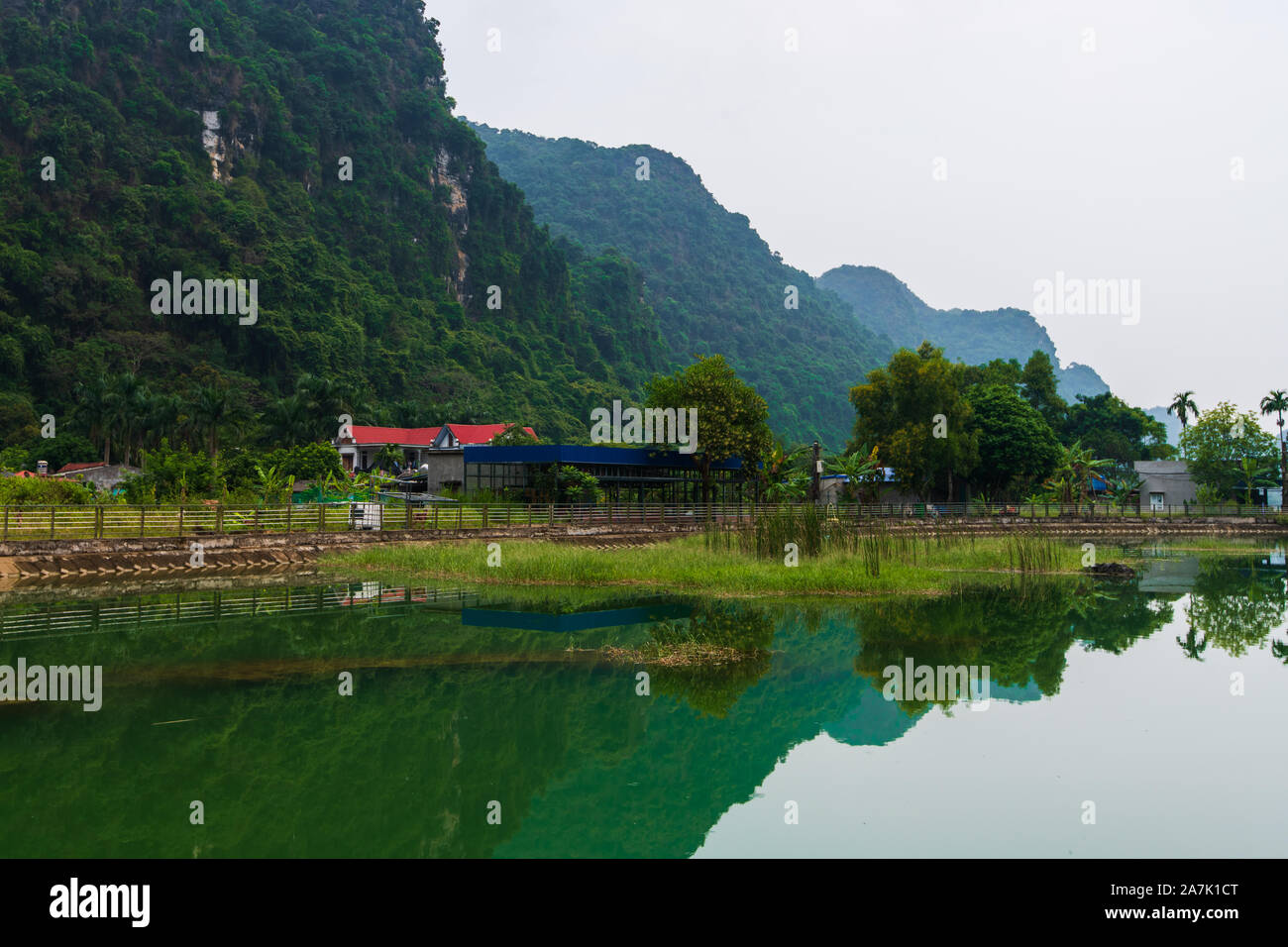 Berge spiegeln sich in eine Glut grüner See auf der versteckten Insel Cat Ba, die regelmäßig mit dem Boot Touren rund um Ha Long Bay besucht wird Stockfoto