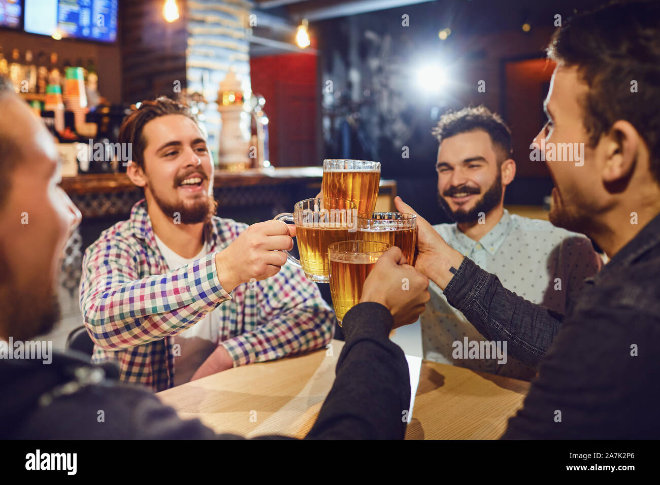 Freunde klirren Bierkrüge in bar Stockfoto