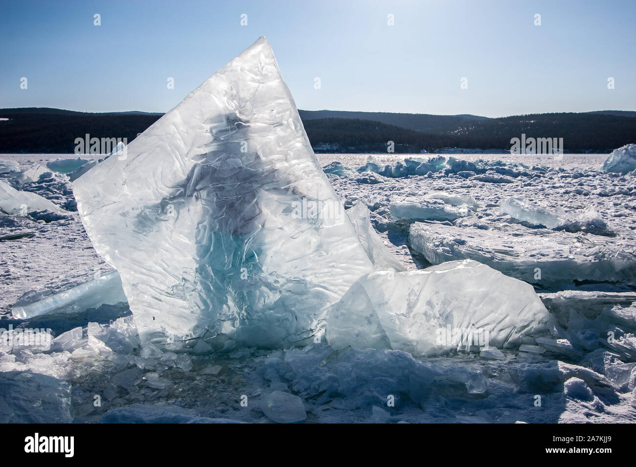 Ein Riesiges Stuck Eis In Den Baikalsee Hinter Der Sich Ein Mann Steht Eingefroren Klarer Himmel Hugel Hinter Einem See Mit Schnee Und Eis Stockfotografie Alamy