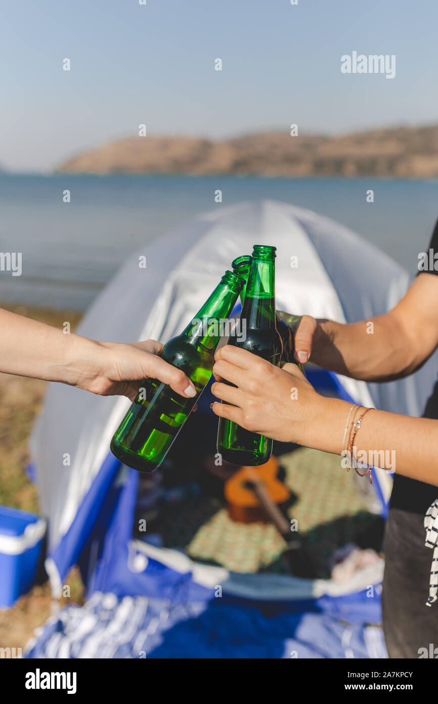 Freunde klirrenden Flaschen Bier am Strand camping Picknick. Stockfoto