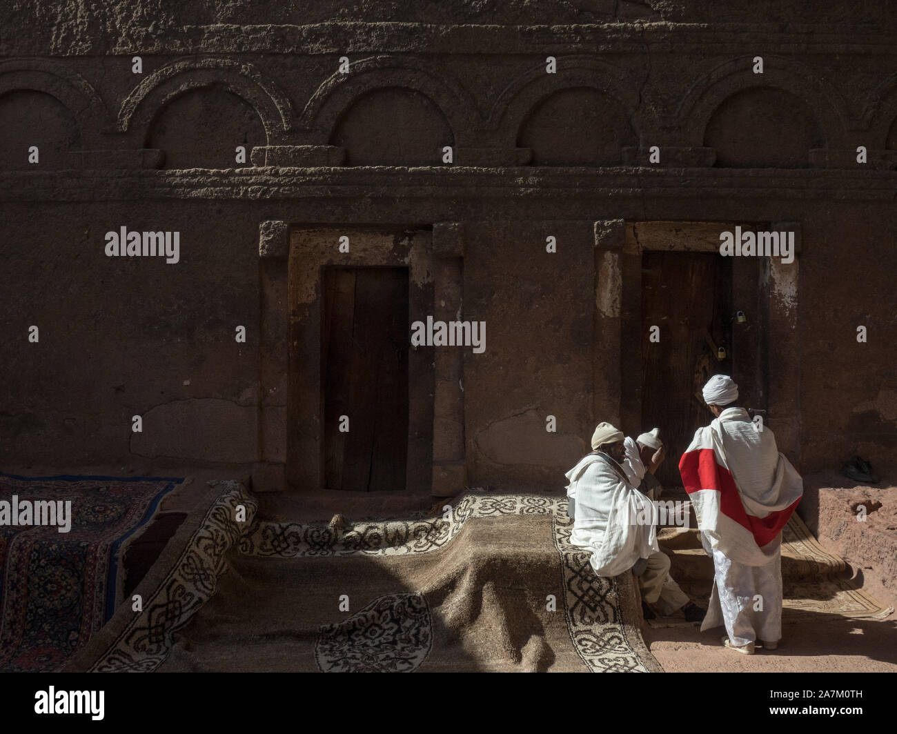 Priester und Mönche sind in Diskussion außerhalb der Tore und Mauern, die in einen Felsen gehauen Biete Maryam, Lalibela, Äthiopien Stockfoto