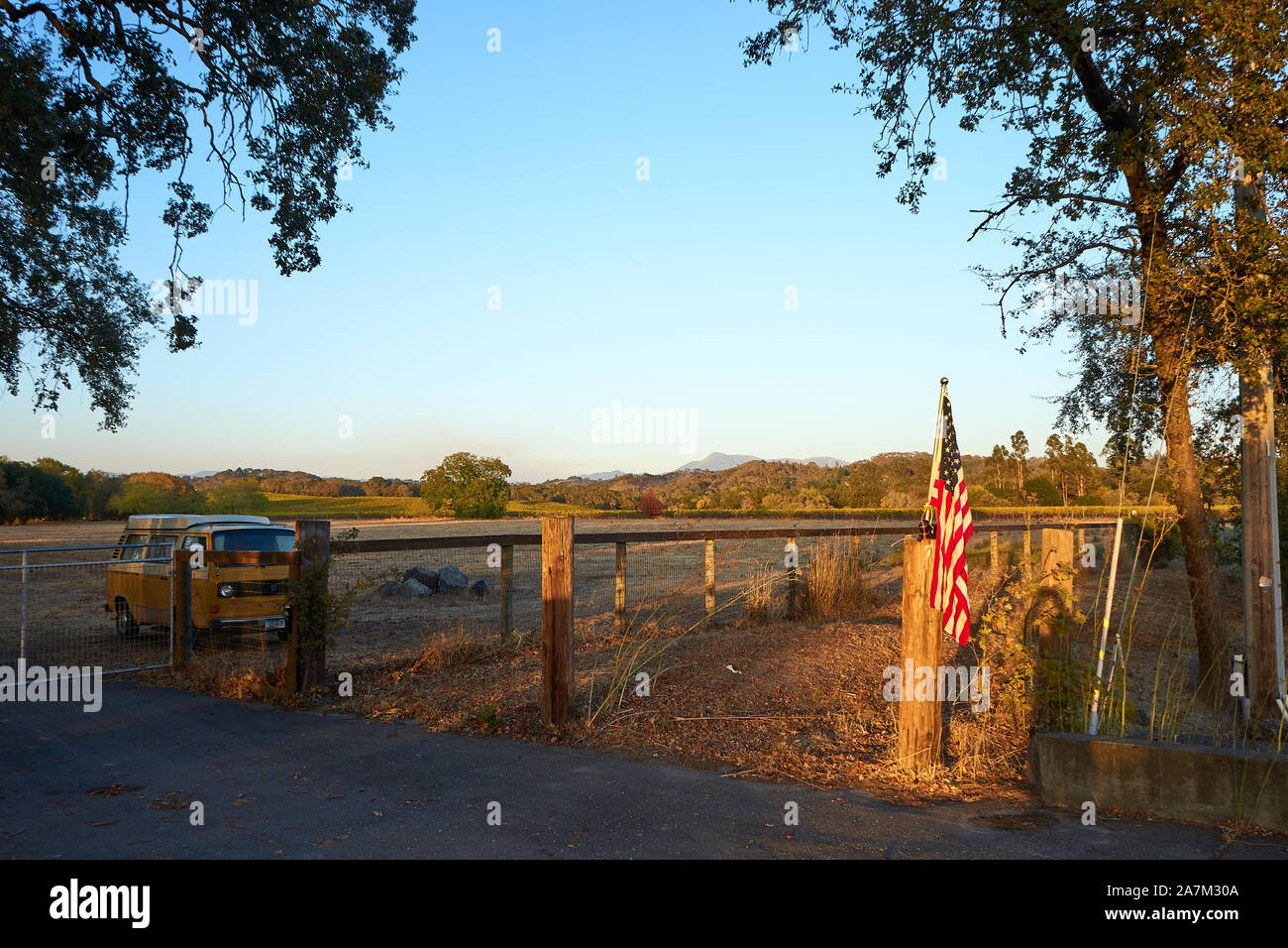 Eine klassische VW Transporter und eine amerikanische Flagge auf einem ländlichen Bauernhof Feld im Windsor, Sonoma County, Kalifornien. Stockfoto