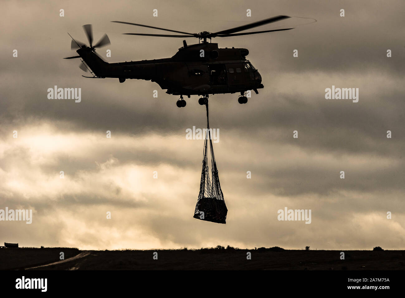 Ein Puma Helikopter der Royal Air Forces trägt eine underslung Laden während einer Übung auf Salisbury Plain Bereich Schulungen Stockfoto