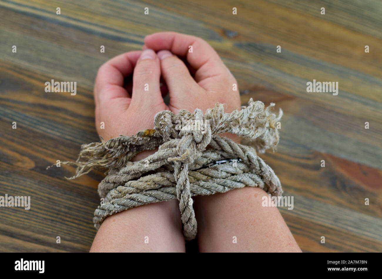 Die Frau Hände mit einem alten Seil gebunden, das Seil grau mit dem Alter ist und Entwirren an den Enden. Es ist möglich, das Bild so zu interpretieren, als Folter. Stockfoto