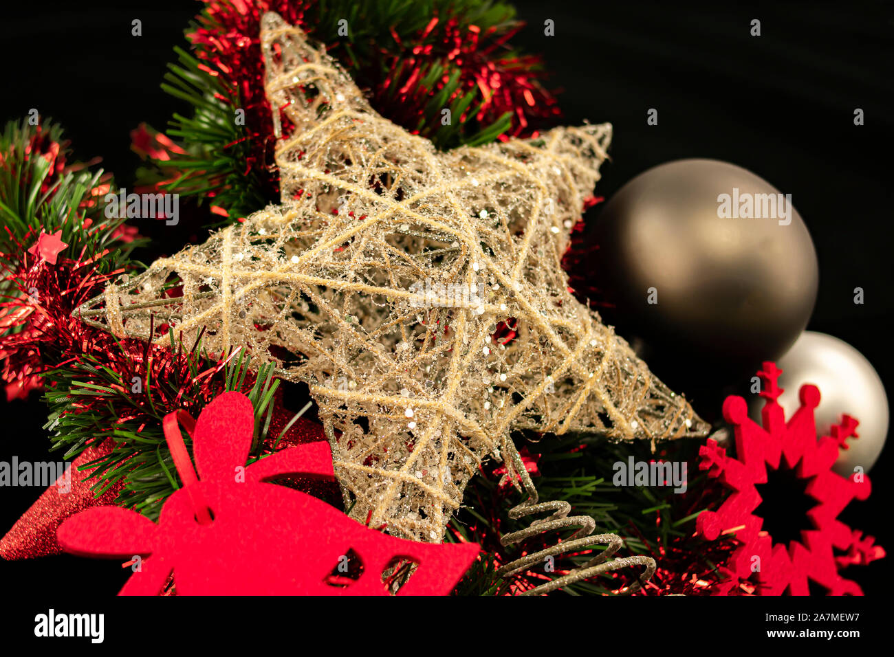 Star Zusammensetzung zusammen liegen mit Schneeflocke und Glockensymbol in rotem Filz mit grauen Kugeln und grüne und rote Lametta Bett, mit hellen Elementen auf Schwarz Stockfoto
