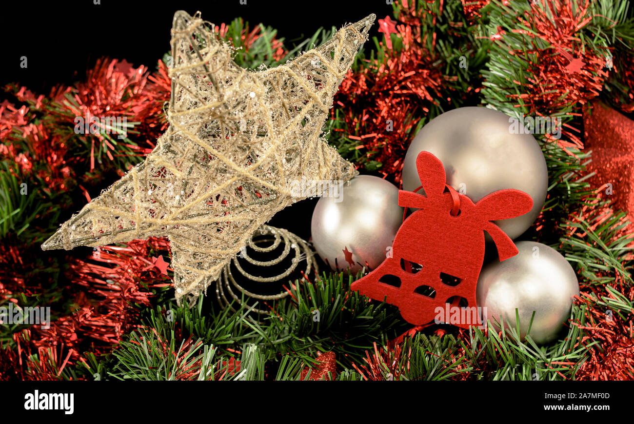 Hintergrund für Weihnachten Gruß aus goldenen Faden, rot-flieltro Bell und graue Kugeln auf roten und grünen Lametta Bett auf schwarzem Hintergrund Stockfoto