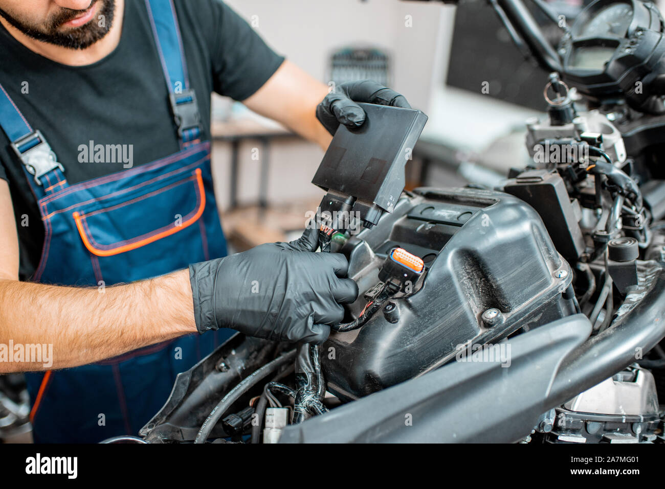 Elektriker oder Schlosser in Schutzhandschuhe verbinden Verkabelung im Motorrad während einer Reparatur in der Werkstatt Stockfoto