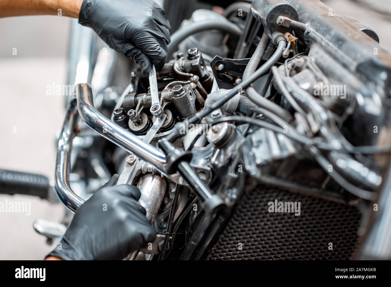 Arbeiter in Schutzhandschuhe Einstellung der Ventile von einer wunderschönen Oldtimer Motorrad an der Werkstatt, Nahaufnahme Stockfoto