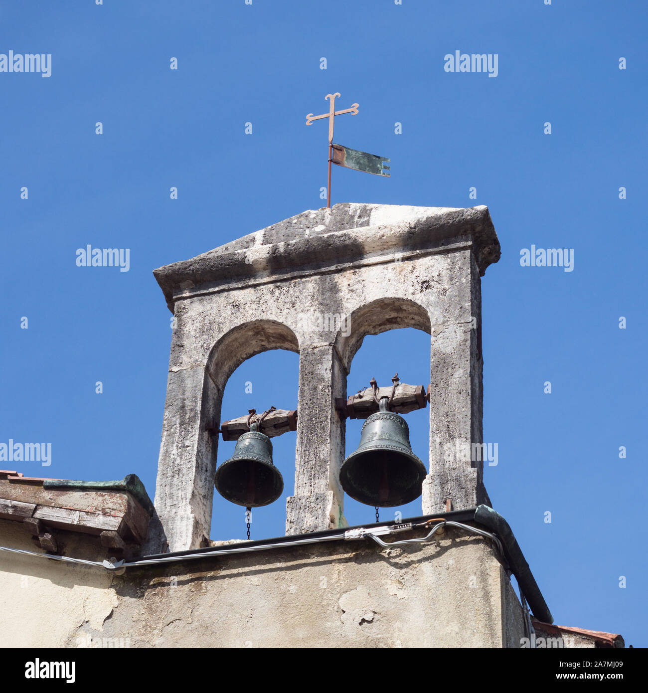 Detail der Glockenturm einer alten kleinen katholischen Kirche. Stockfoto