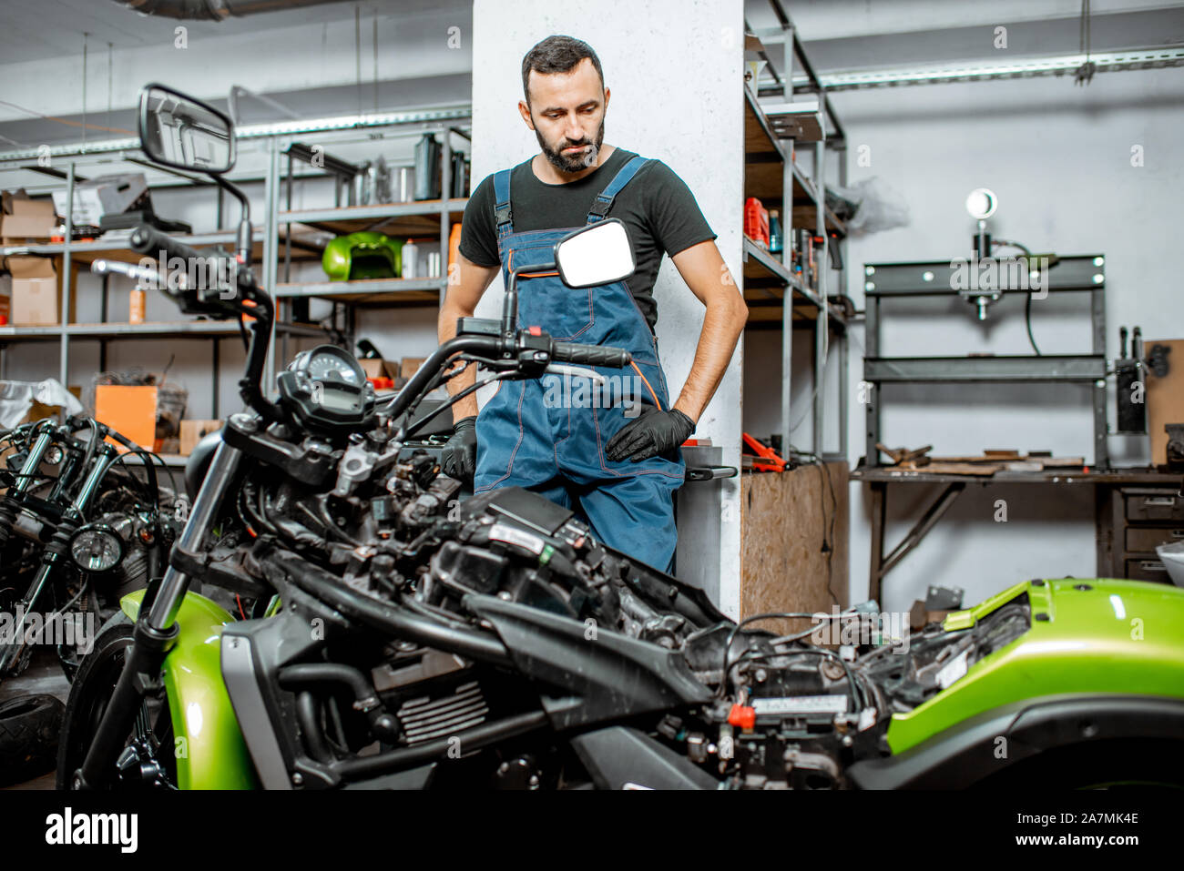 Porträt einer Biker oder Handwerker in Overalls in der Nähe der Motorrad  stehen während der Reparatur in der Werkstatt Stockfotografie - Alamy