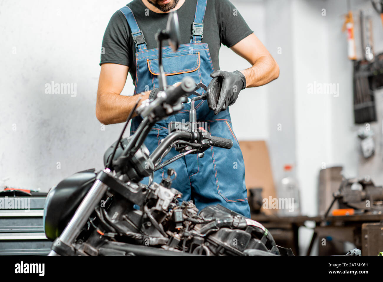Mechaniker in Latzhosen Motorrad reparieren, Messen spiegel halter für  Ersatz oder Tuning bei dem Workshop im Innenbereich Stockfotografie - Alamy