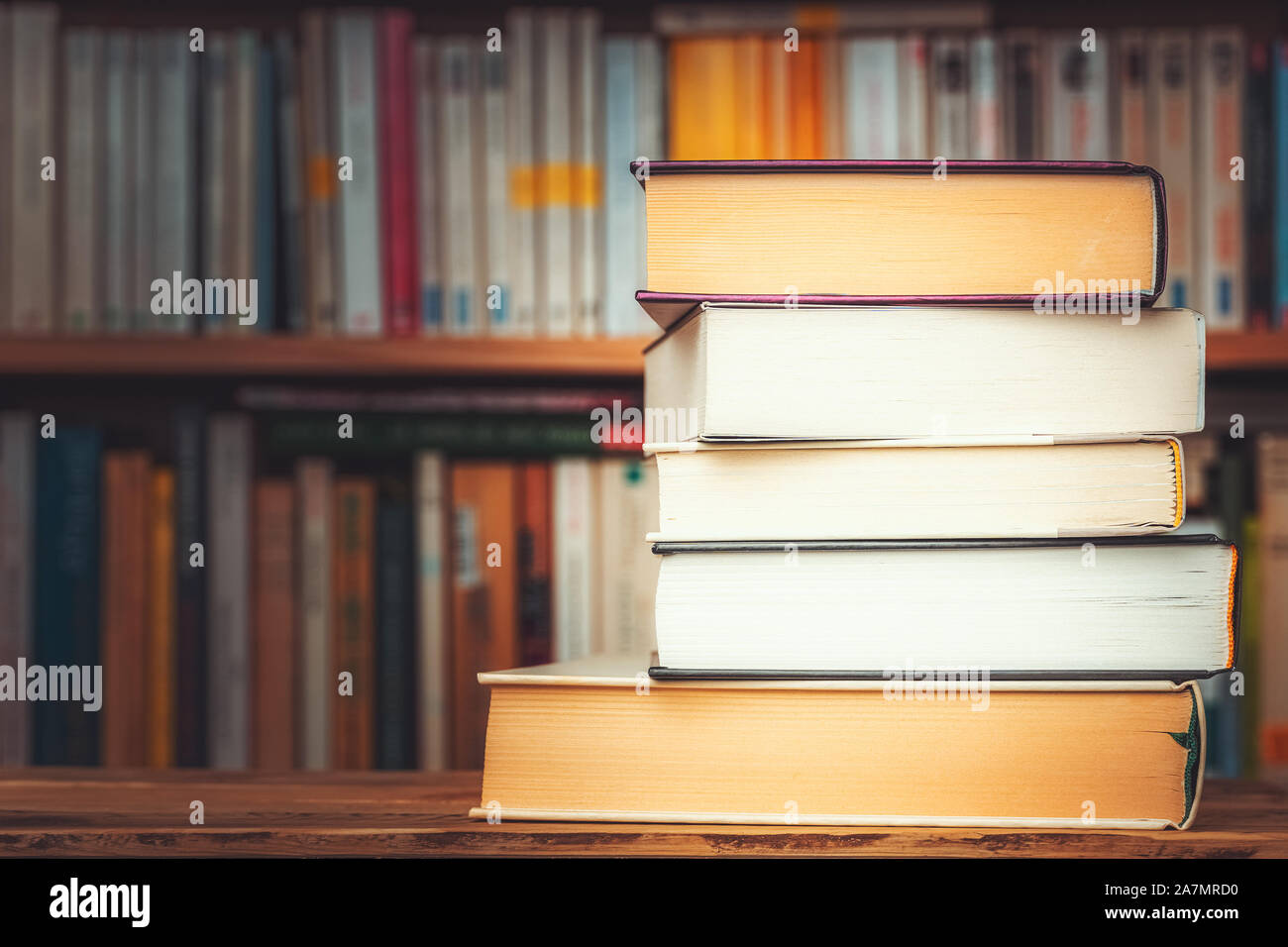 Stapel der großen Bücher mit verschwommenen Bücherregal im Hintergrund und Kopieren. Wissen, Lesen, Studieren, Alphabetisierung oder Literatur anschauliches Konzept. Stockfoto