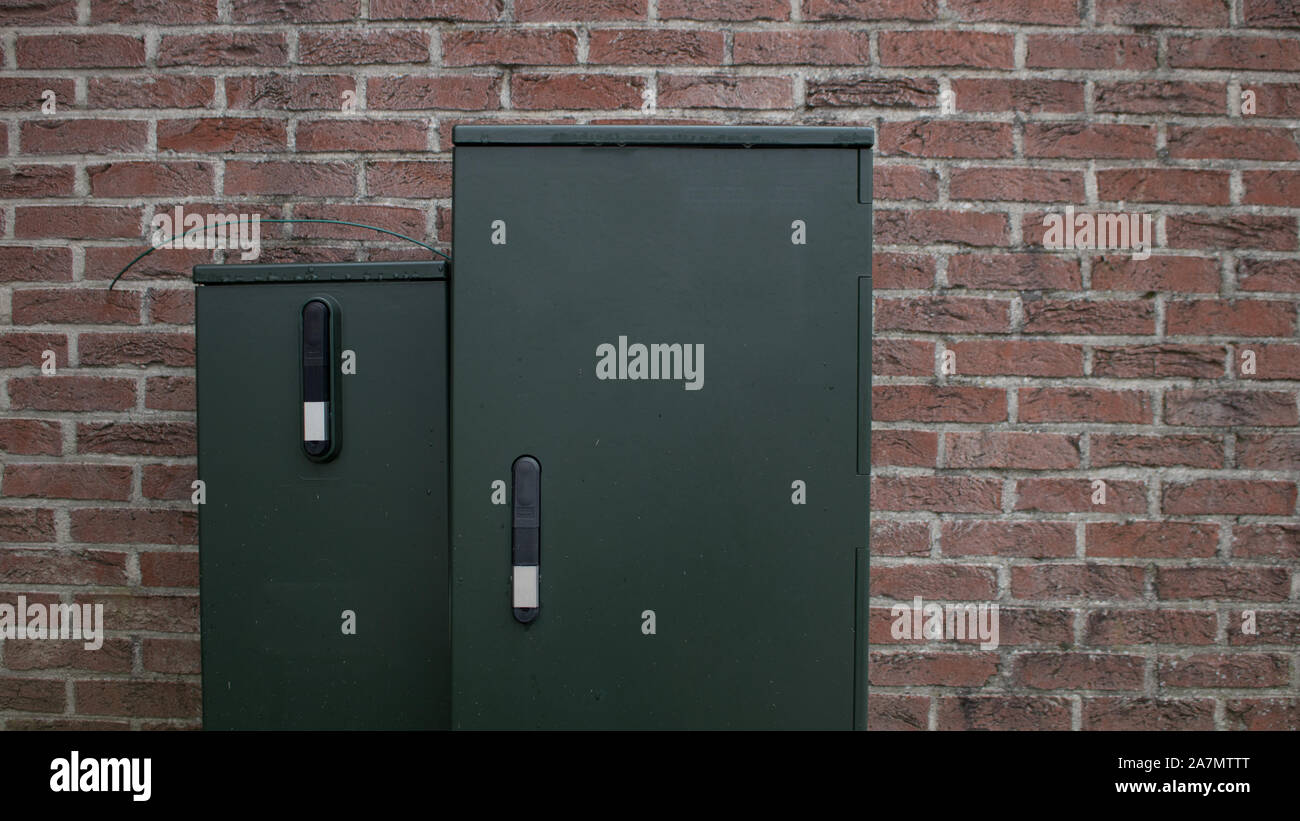 Electric Grün Distribution Box hinter einer Mauer isoliert Stockfoto