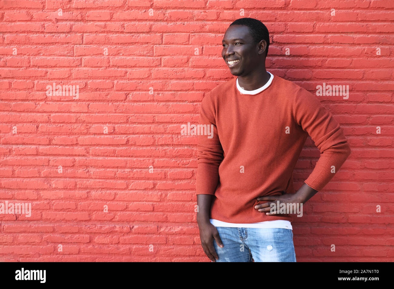 Afrikanische jungen Mann lächelte und lehnte sich auf Rote Wand Stockfoto