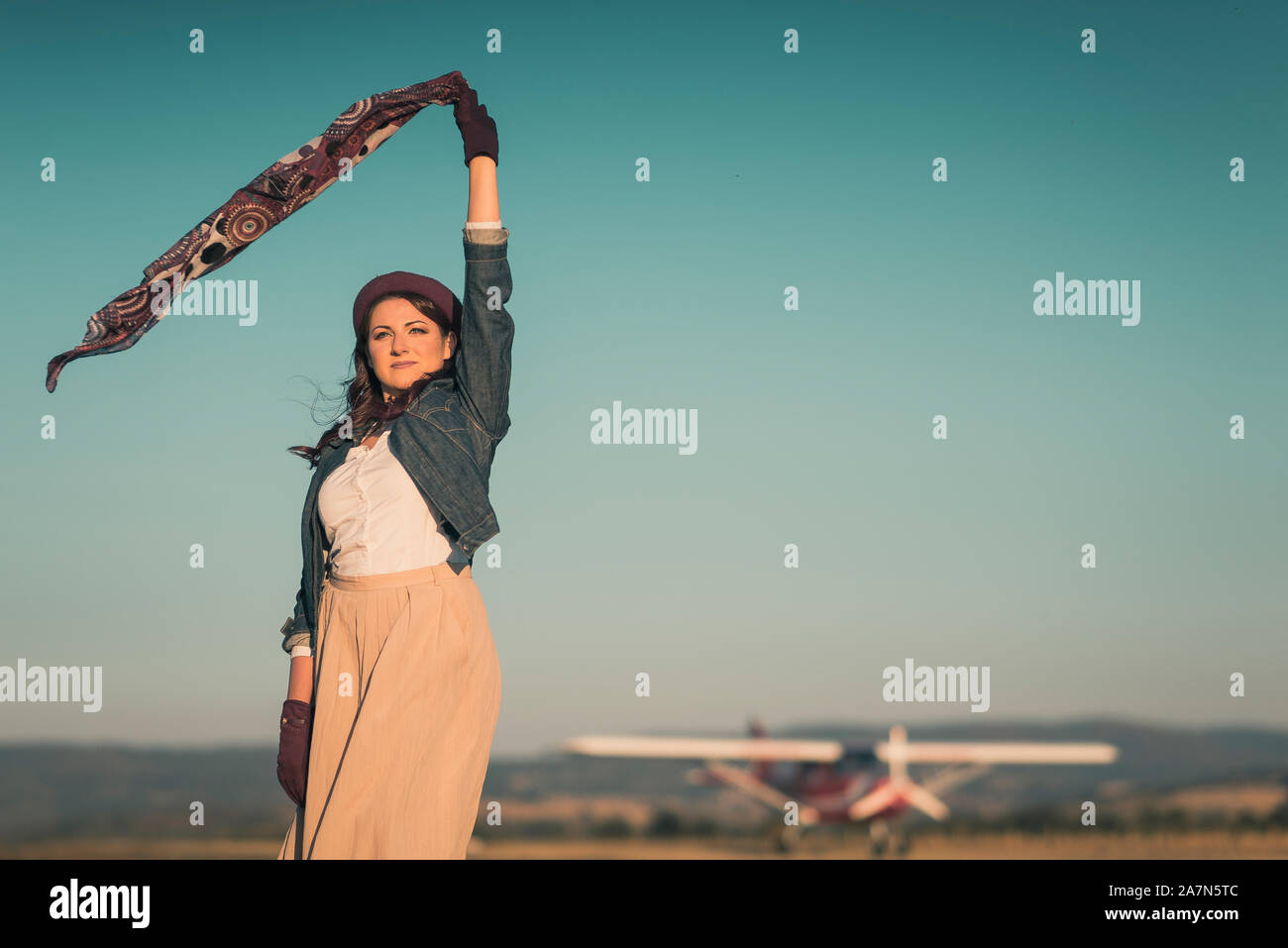 Junge Frau mit bis Schal im Wind auf Field Airport Stockfoto