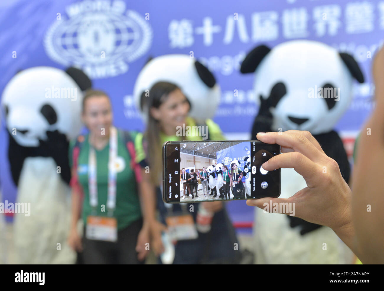 Gäste posieren für Fotos mit chinesischen Arbeitern in Panda Kostüme während der 2019 World Police und Fire Games in Chengdu City, Südwesten Chi gekleidet Stockfoto