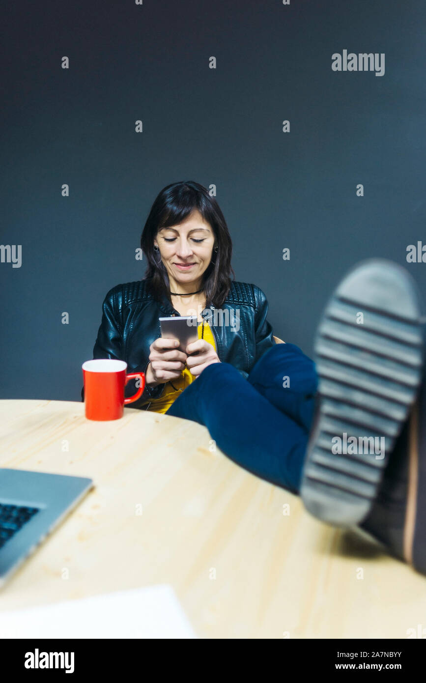 Frau mit Kaffee und Smartphone in Ihrem Büro Stockfoto