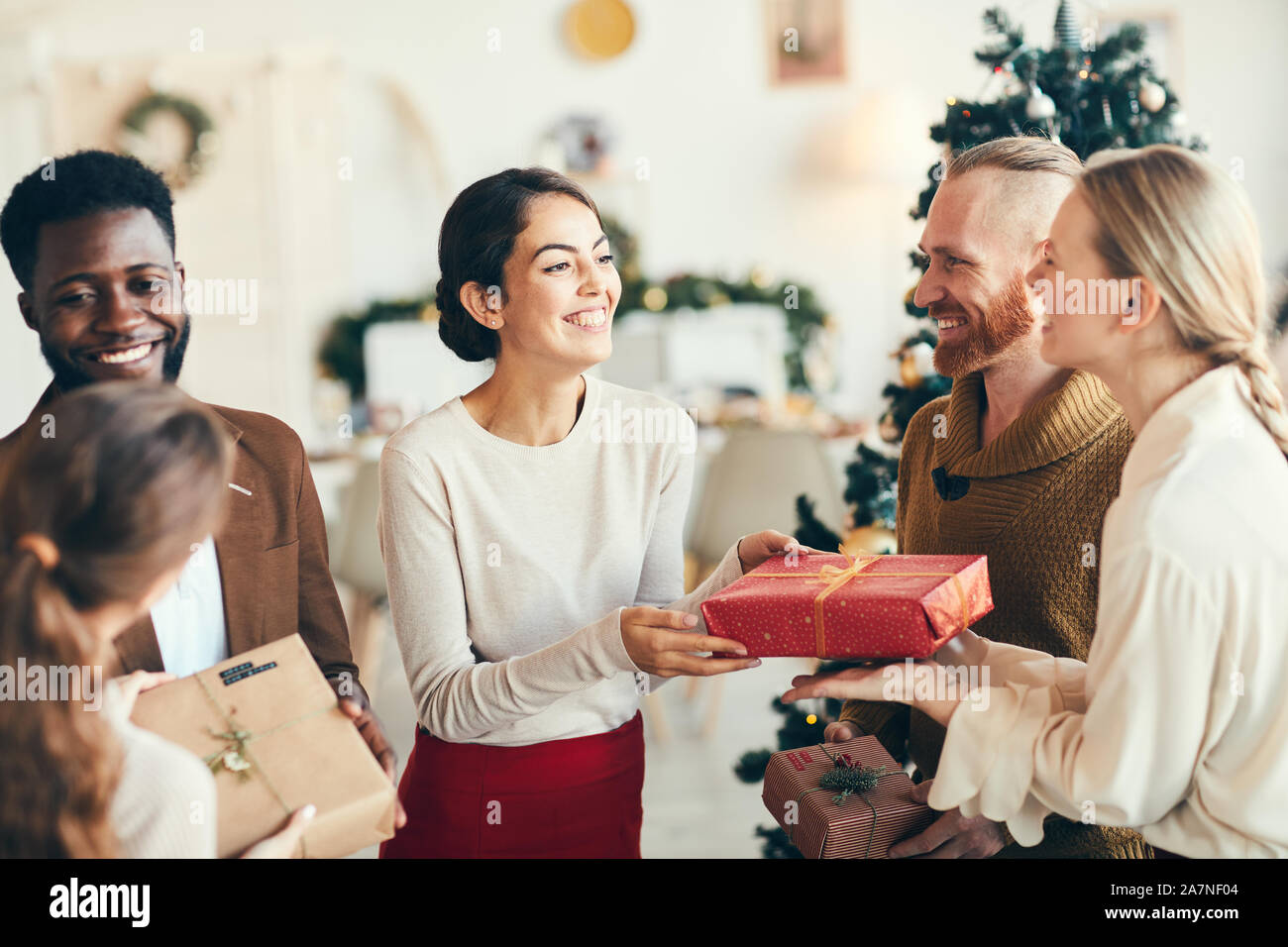 Gruppe von eleganten jungen Menschen den Austausch von Geschenken und freundlich lächelnd während der Weihnachtsfeier, kopieren Raum Stockfoto