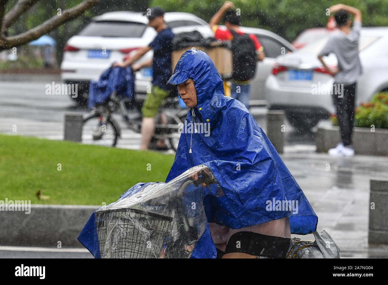Ein Radfahrer tragen einen Regenmantel und einen Hut gegen schwere Unwetter von Typhoon typhoon Wipha, die 7. des Jahres verursacht, fährt auf einer Straße in der Stadt Guangzhou Stockfoto