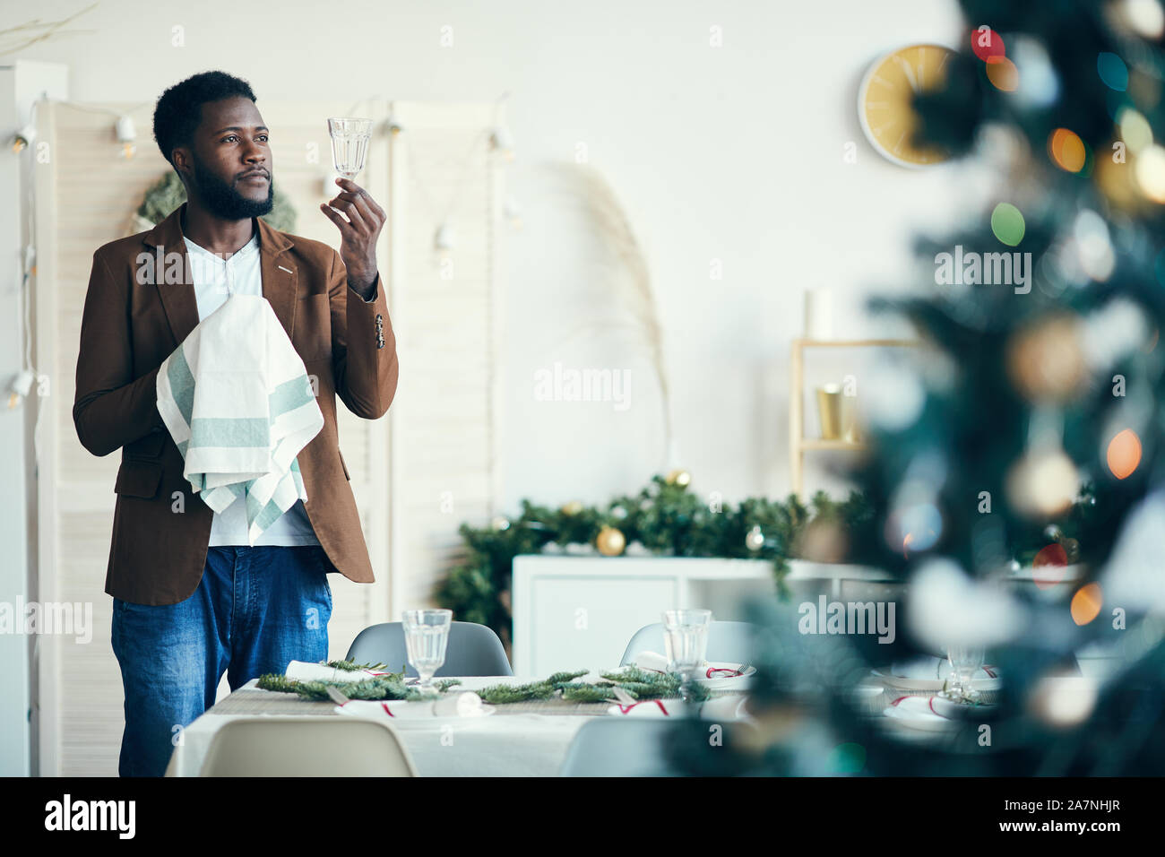 Porträt der jungen Afrikaner Mann wischen Kristallgläsern beim Einstellen der Tisch für Weihnachtsfeier, kopieren Raum Stockfoto