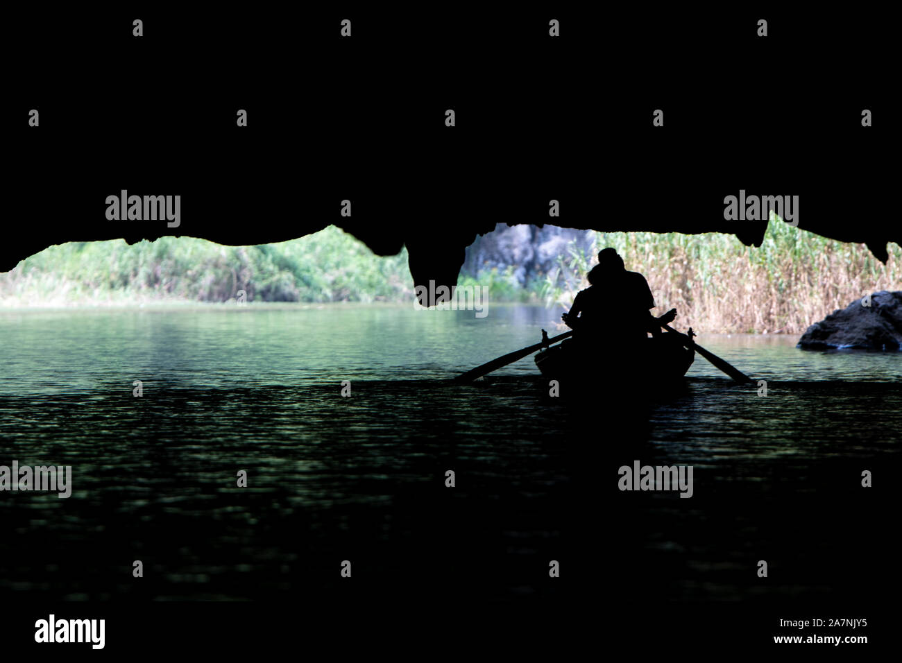 Eine Zeile Boot voller Touristen auf einer Flussfahrt tour ergibt sich aus unter einem großen Tropfsteinhöhle in der Tam Coc, Northern Vietnam Stockfoto