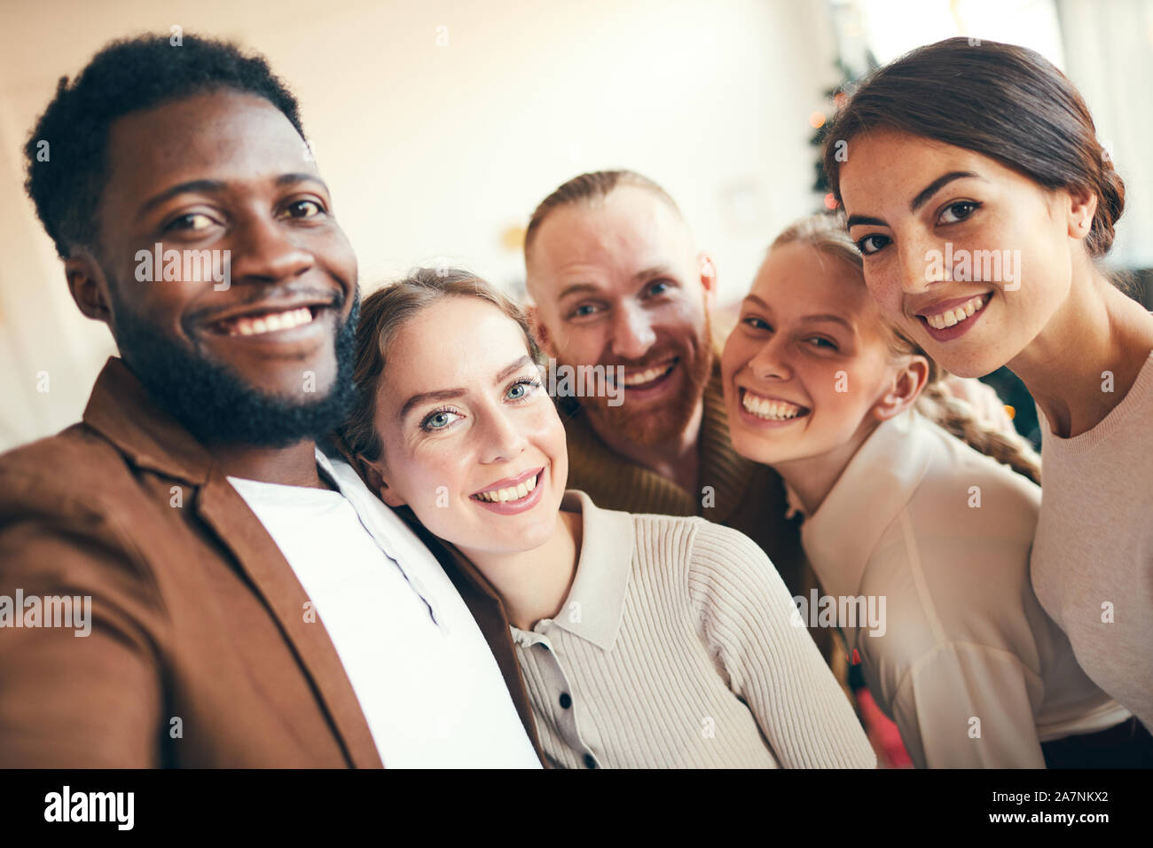 Multi-ethnischen Gruppe von eleganten erwachsenen Menschen in die Kamera lächeln, während der Einnahme von selfie Foto während der Weihnachtsfeier Stockfoto