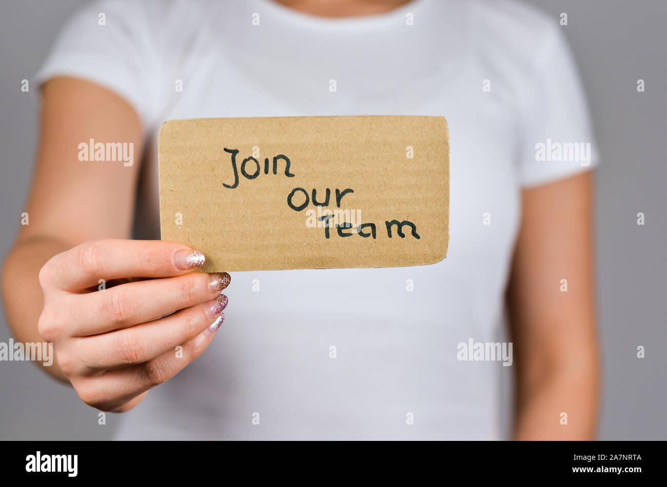 Nahaufnahme von jungen Frauen Hand, die Pappe Papier mit werden Sie Mitglied in unserem Team Satz Text. Stockfoto