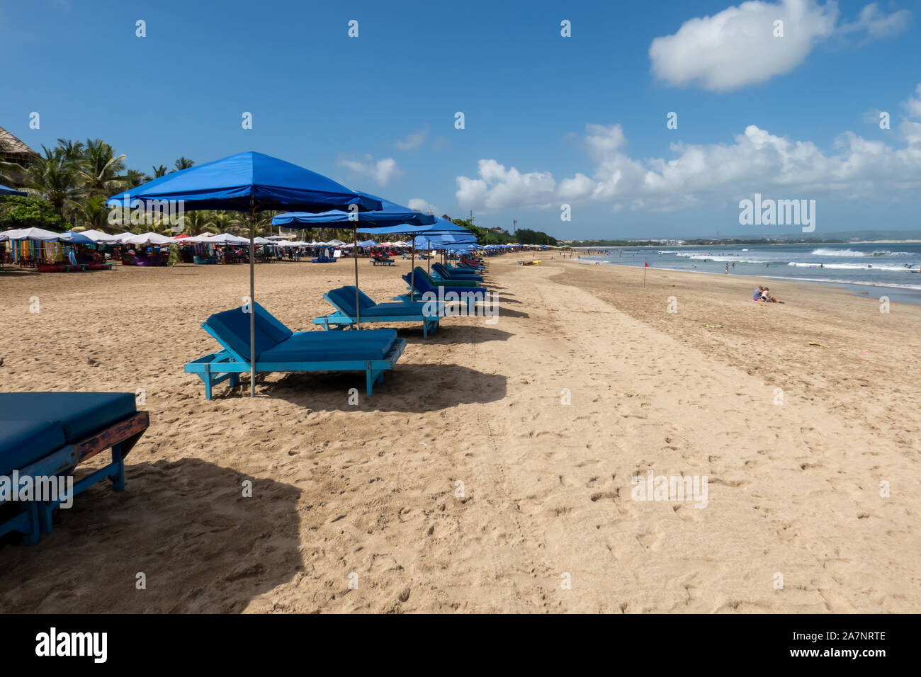 Eine Reihe von leeren Liegestühlen und Sonnenschirmen für Touristen am Strand von Kuta Bali Indonesien warten Stockfoto