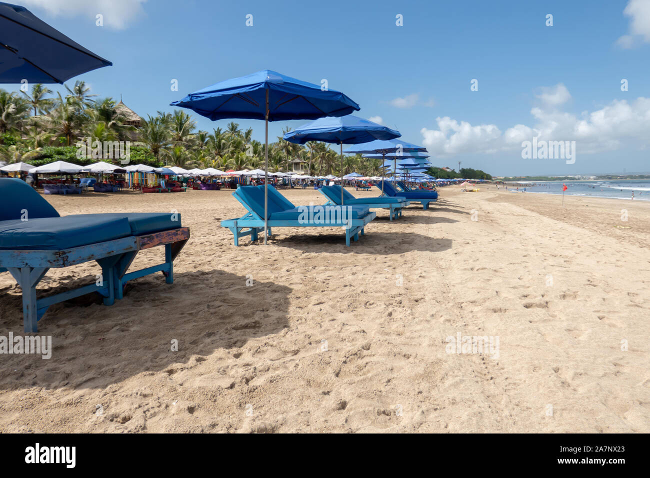 Eine Reihe von leeren Liegestühlen und Sonnenschirmen für Touristen am Strand von Kuta Bali Indonesien warten Stockfoto