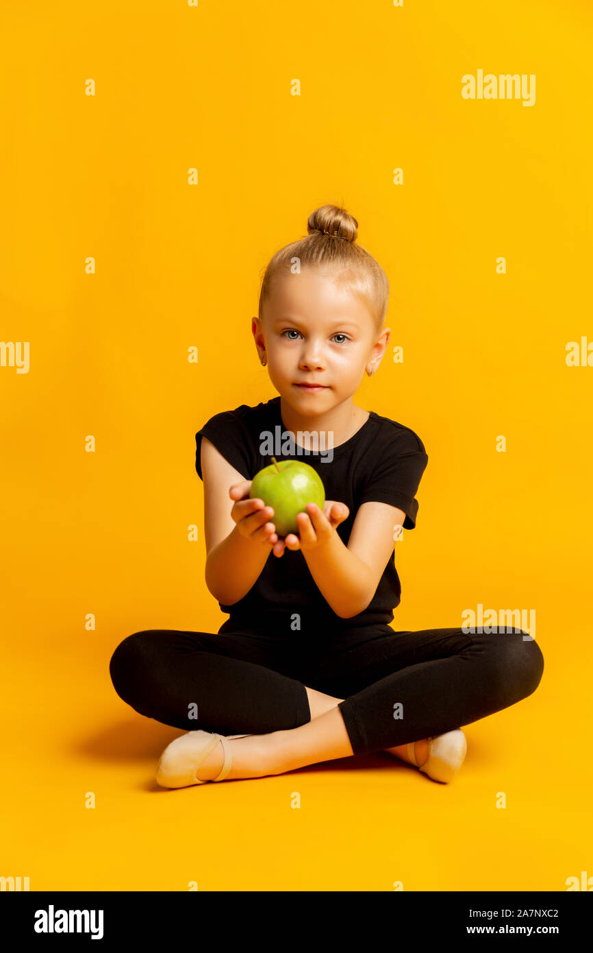 Konzept der Kid's Sport und gesunde Ernährung. Happy fröhlich aufgeregt zuversichtlich gymnast Mädchen hält einen grünen frischen Apfel Stockfoto