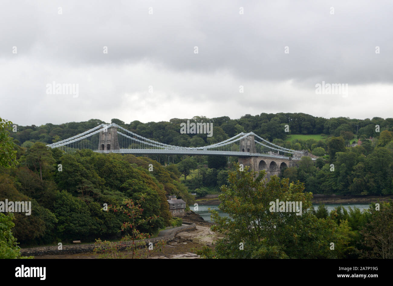 Die Menai Suspension Bridge ist eine Hängebrücke, die die Menai Strait zwischen der Insel Anglesey und dem Festland von Wales überspannt. Stockfoto