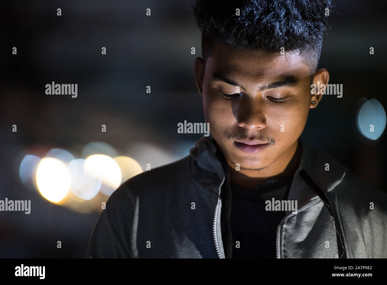 Gesicht der jungen asiatischen Mann mit Phone in den Straßen der Stadt bei Nacht Stockfoto