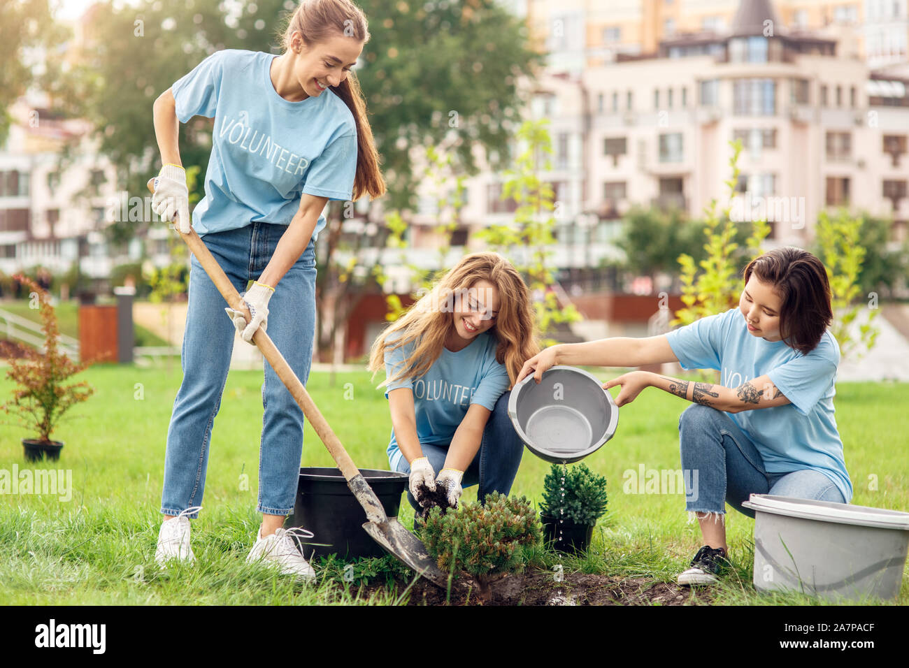 Freiwilligenarbeit. Die jugendlichen Freiwilligen im Freien Anpflanzen von Bäumen graben Boden Gießen von Wasser treibend Stockfoto
