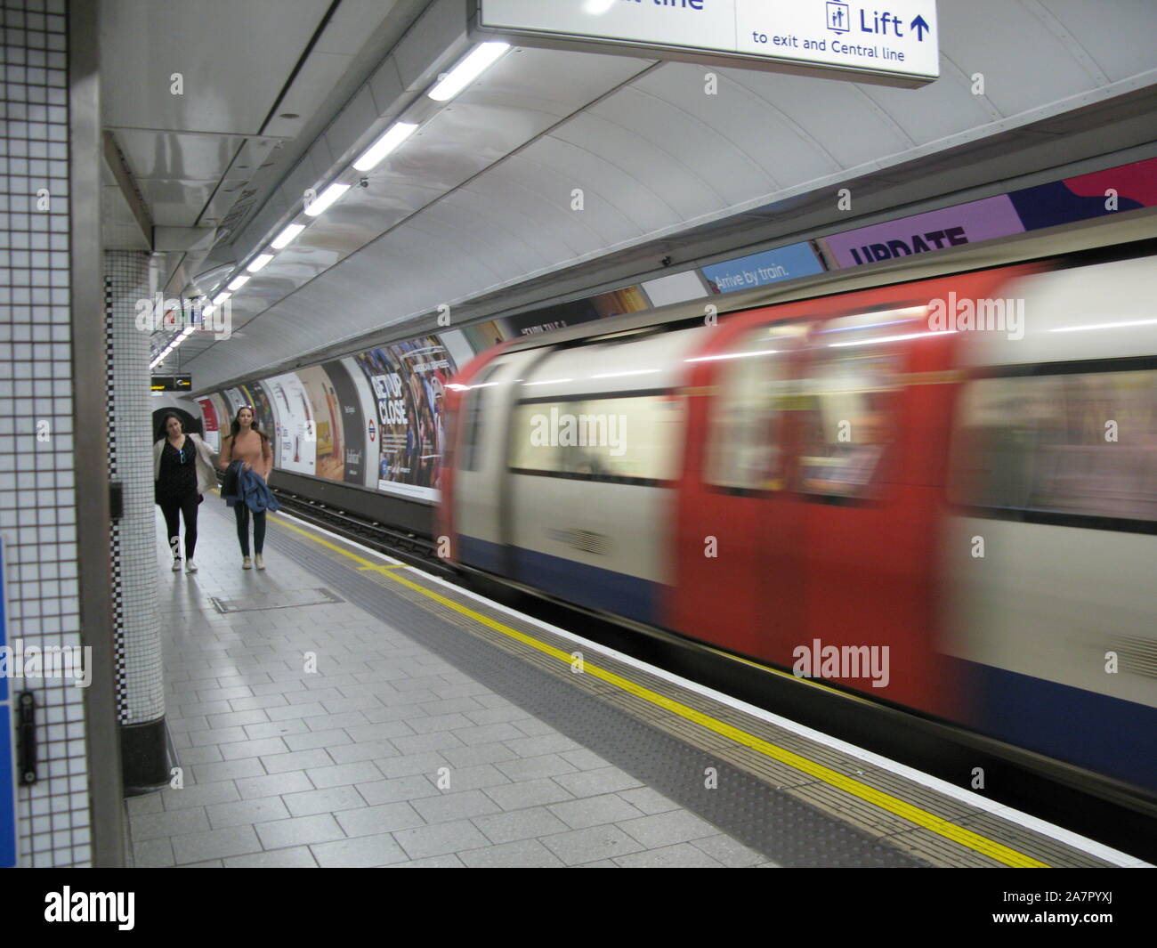 Nur wenige Leute auf einem Bahnsteig der Londoner U-Bahn, der den Zug abfährt Der Station Stockfoto